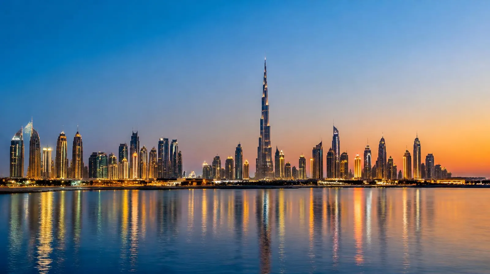 Skyline von Dubai mit hohem Turm am Wasser in der Abenddämmerung