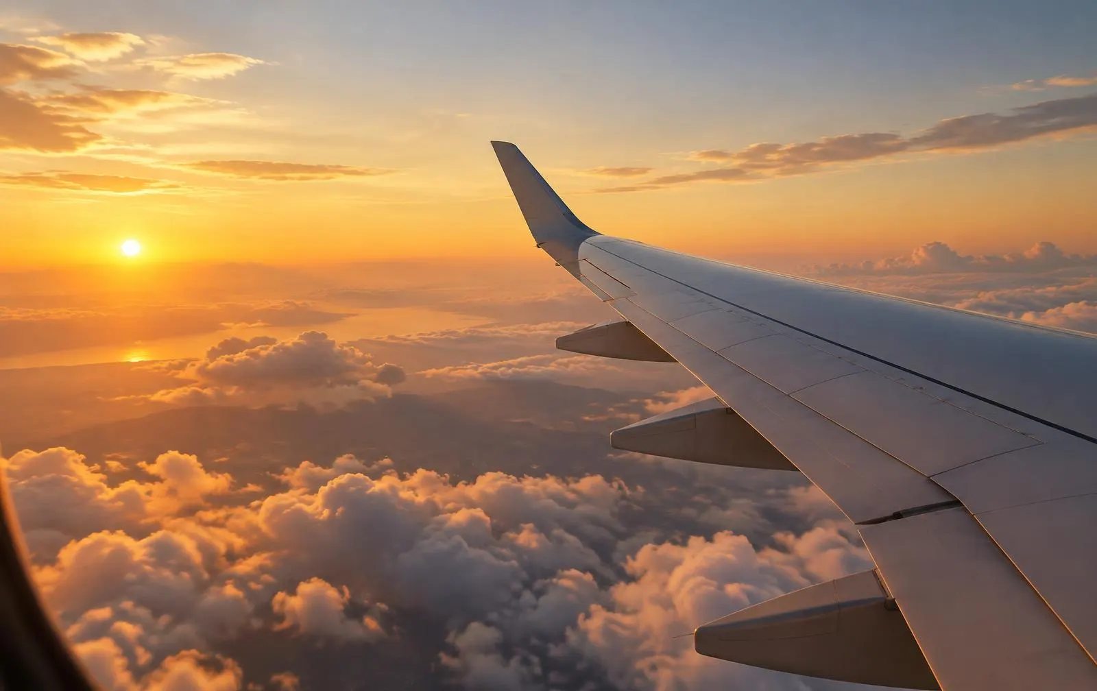 Blick aus dem Flugzeugfenster auf Tragfläche und Wolken im Abendlicht