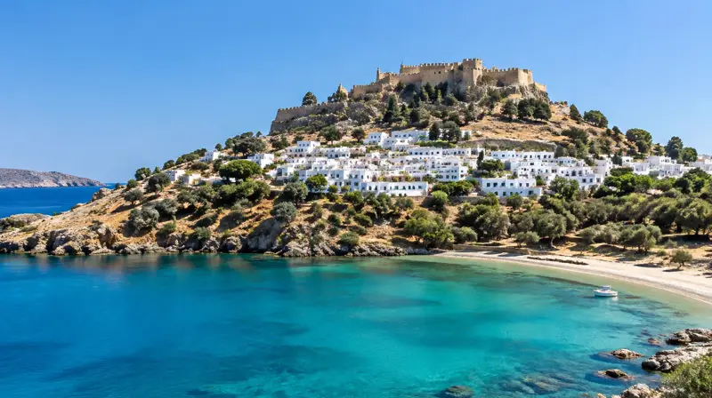 Weißes Dorf Lindos unter der Akropolis mit türkiser Bucht auf Rhodos